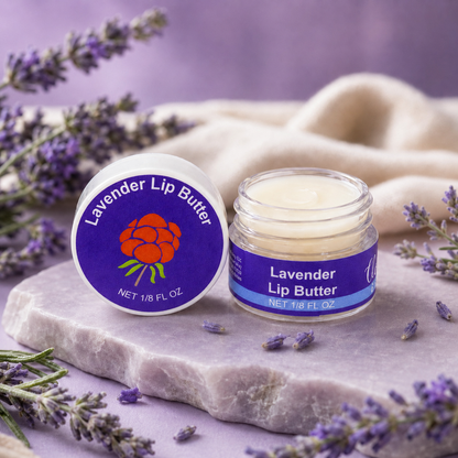 Open jar of Cloudberry Beauty Lavender Lip Butter on stone with lavender flowers and soft purple fabric.