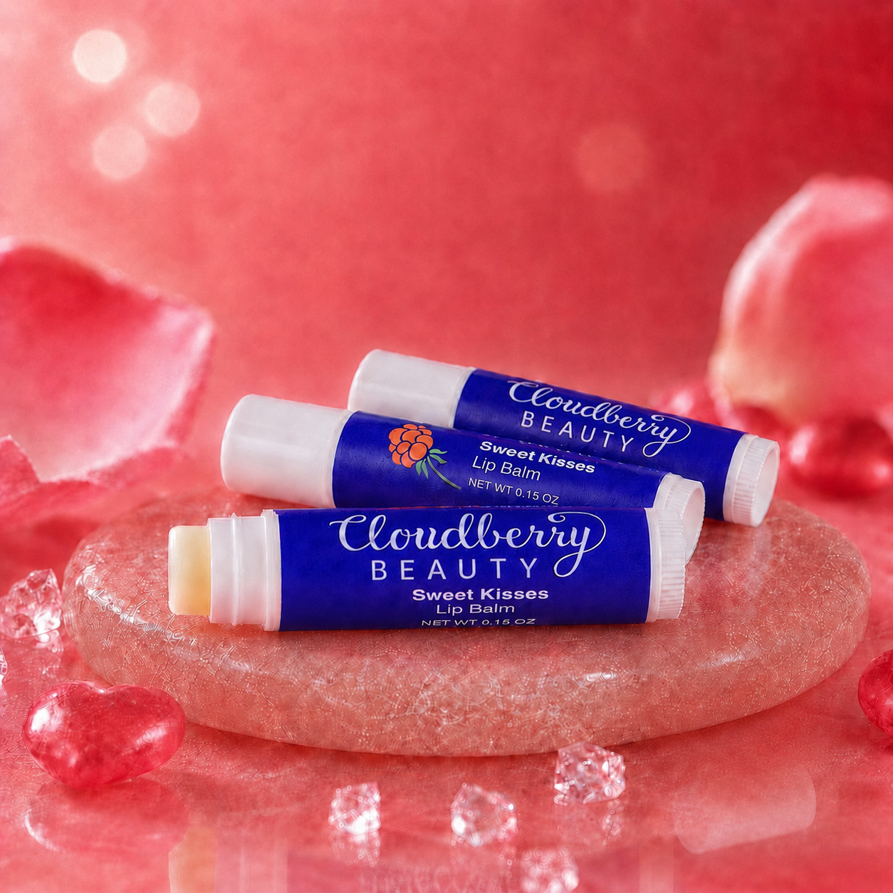 Three Cloudberry Beauty Sweet Kisses Lip Balm tubes displayed on a pink stone pedestal with heart accents.