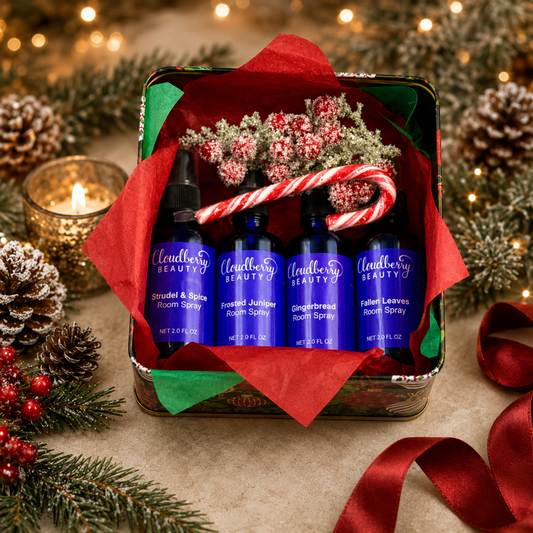 Open Christmas gift tin with four Cloudberry Beauty room sprays, candy canes, greenery and red ribbon.