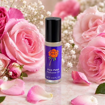 Cloudberry Beauty Pink Petal Perfume Oil roll-on bottle surrounded by lush pink roses and petals.